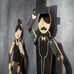 Gentleman puppet on grey wall in close-up with flamenco dancer companion visible in background
