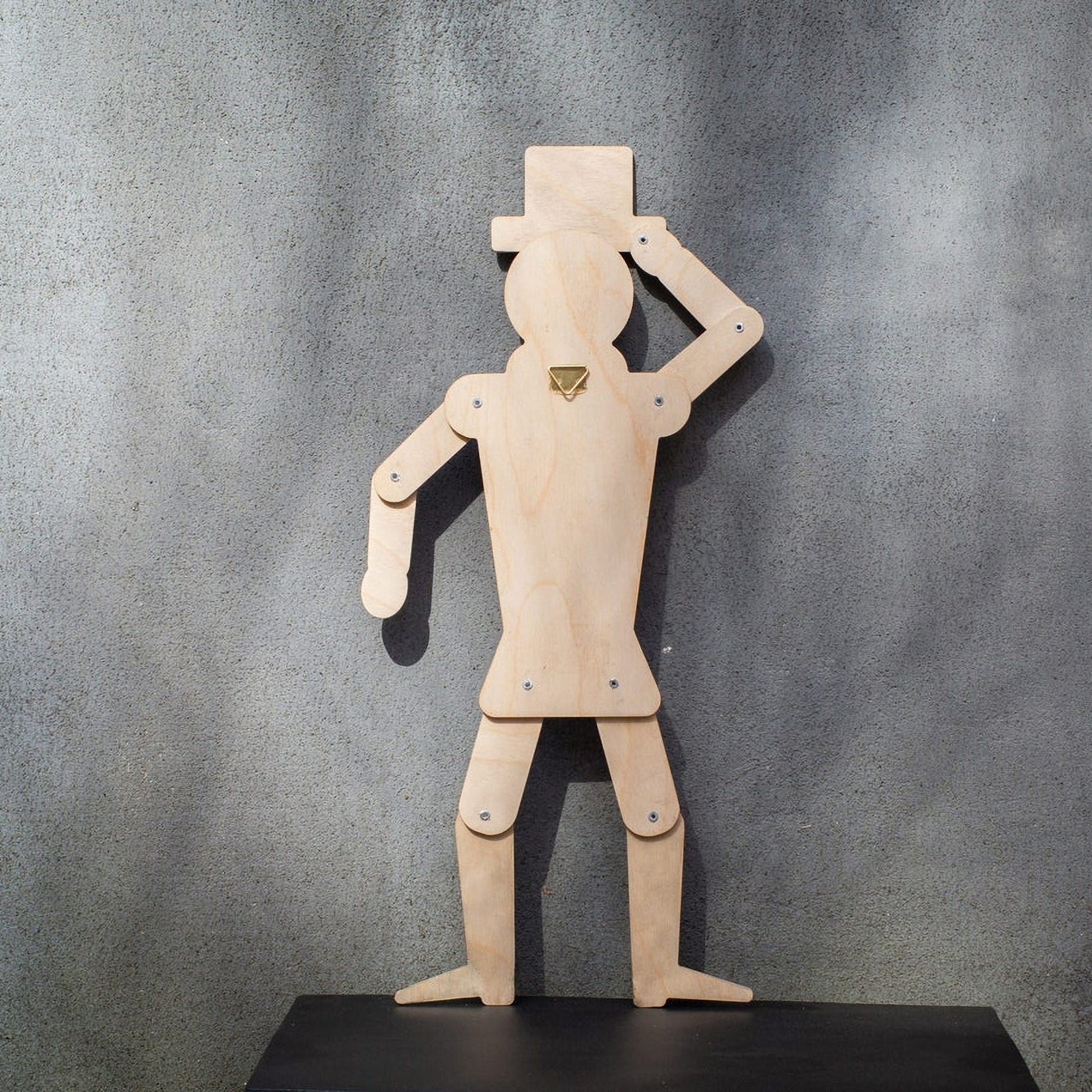 Back view of wooden gentleman puppet showing jointed construction and brass wall hook on grey background