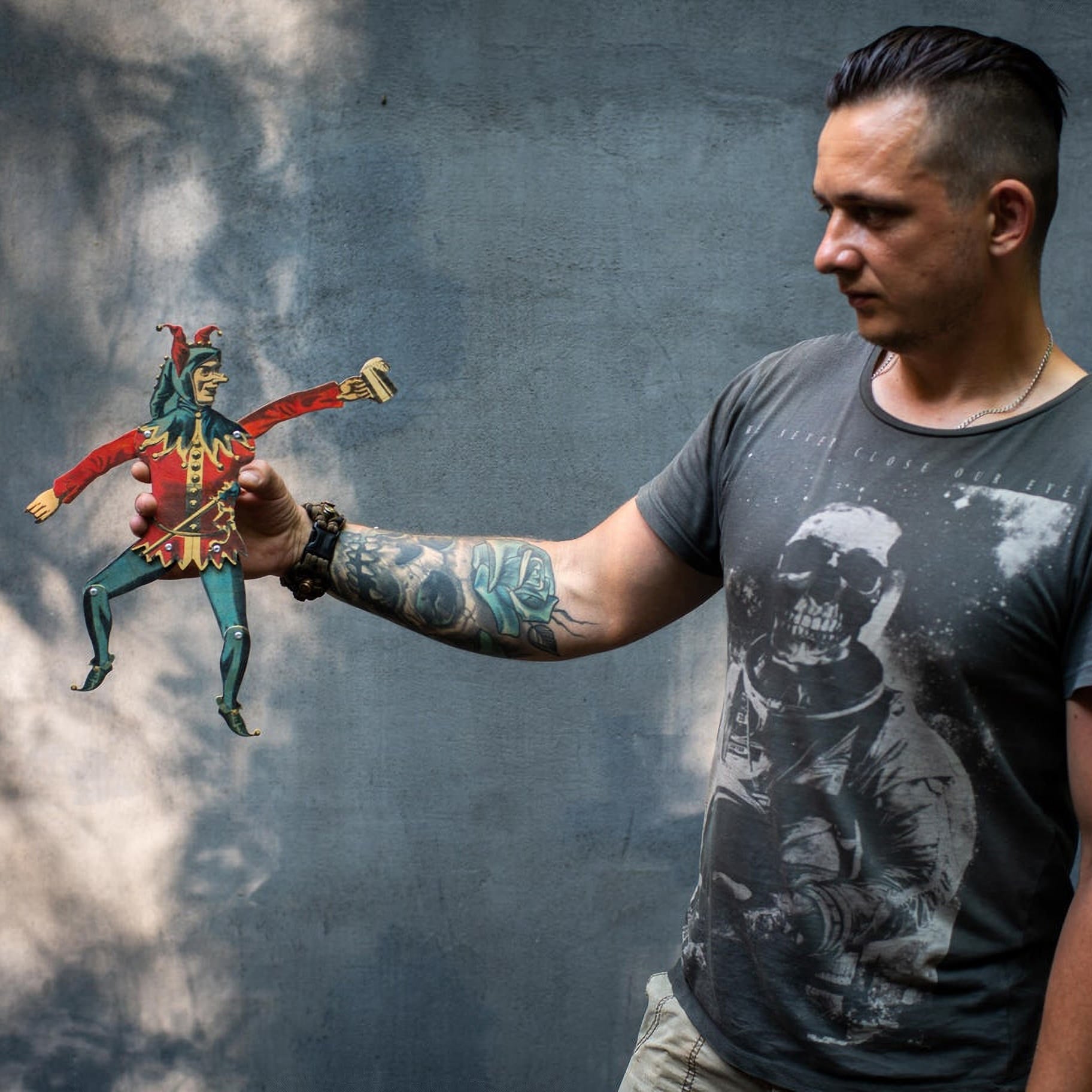 man holding articulated plywood jester puppet showing movable limbs
