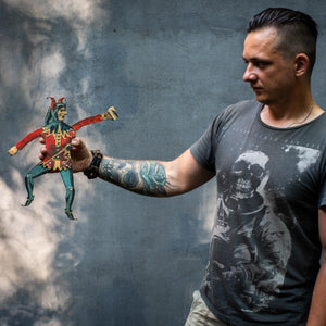 man holding articulated plywood jester puppet showing movable limbs