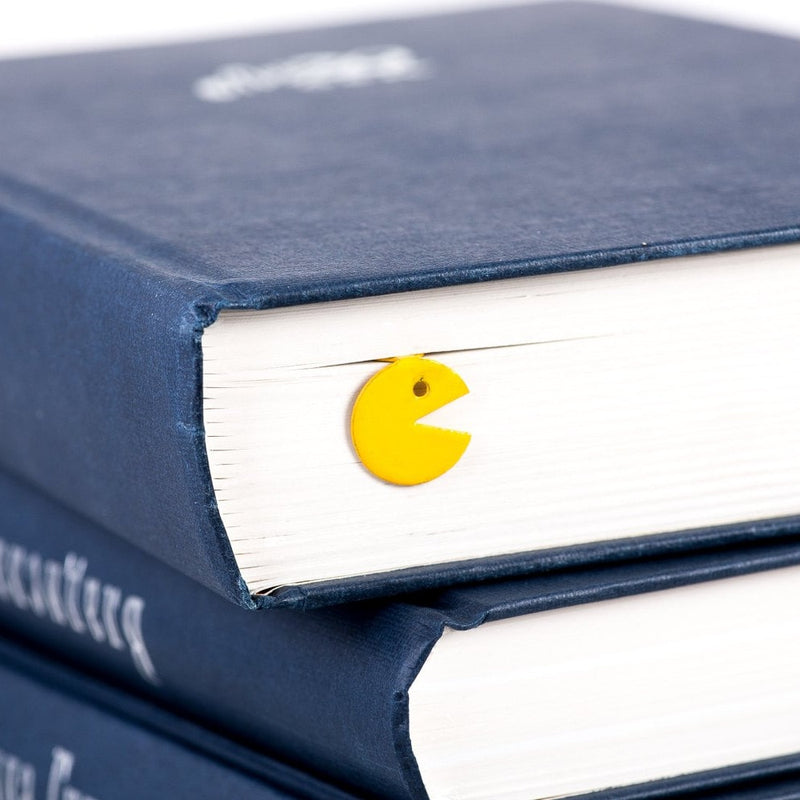 Yellow Monster metal bookmark in gold shown with a stack of books