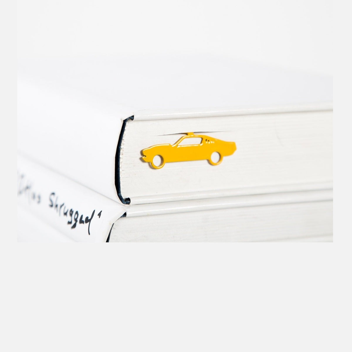 Yellow Muscle Car metal bookmark in gold resting on the pages of an open book