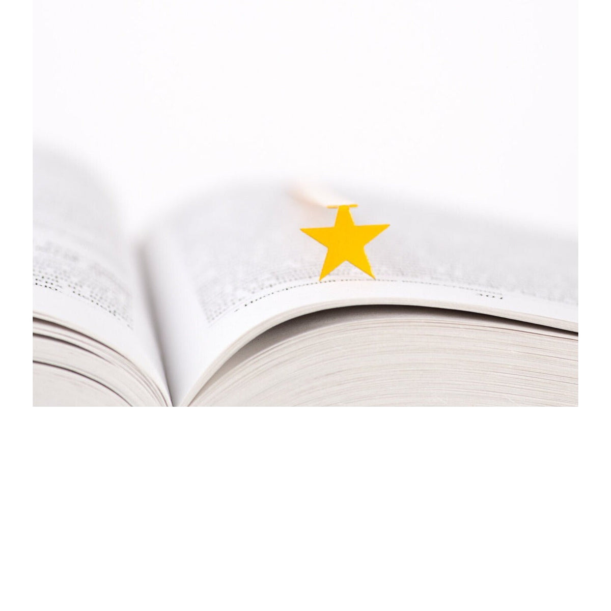 Yellow Star metal bookmark in gold resting on the pages of an open book