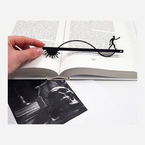 Zombie When the Night Comes metal bookmark held in a hand above an open book